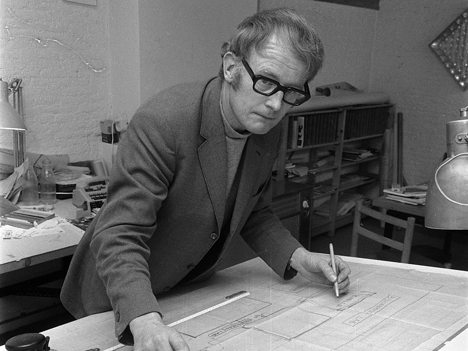 Architect voorovergebogen over een bouwtekening, potlood in de hand