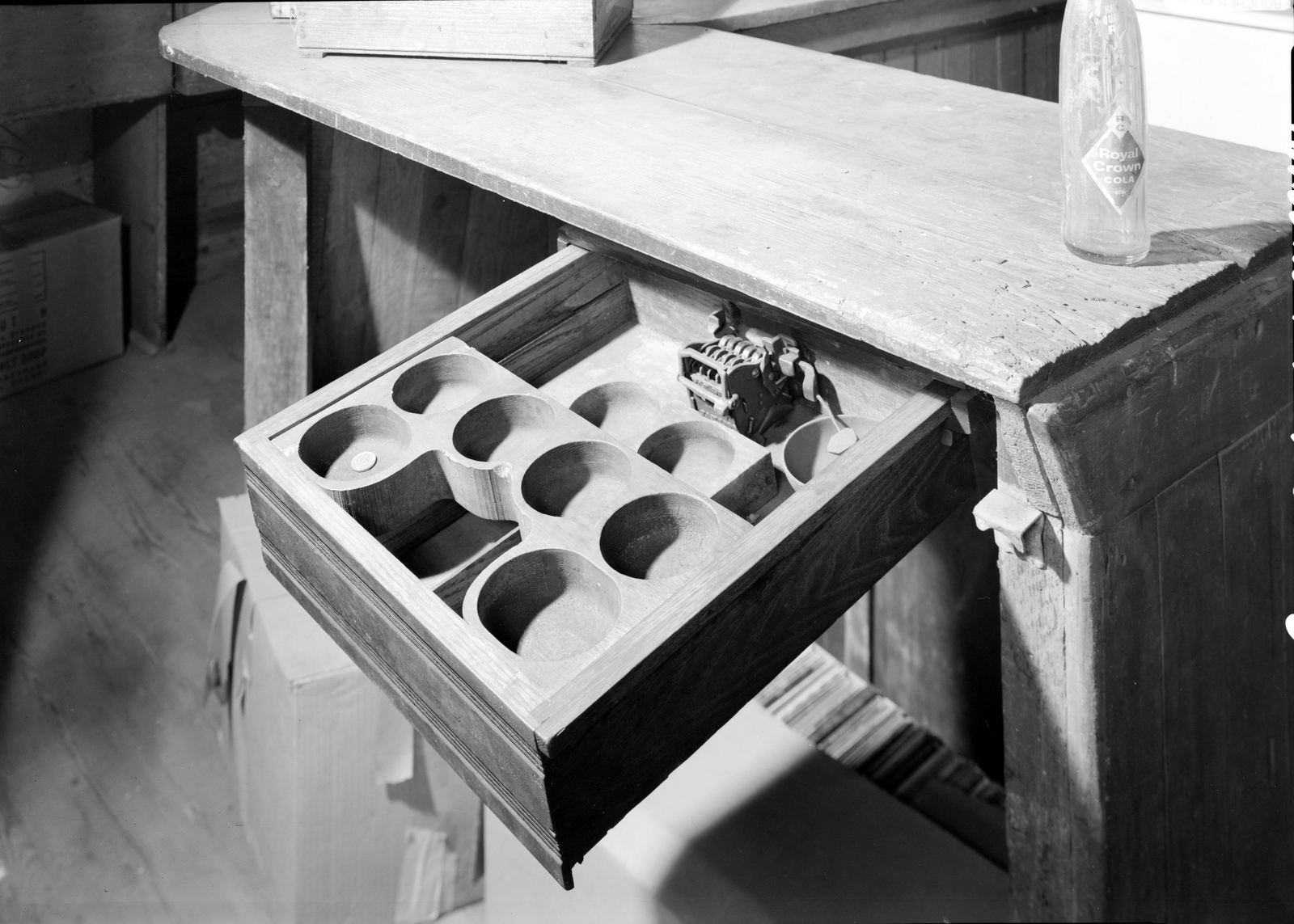 Houten geldlade met voor elke munt een eigen uitgefreesde kuil, in een winkel