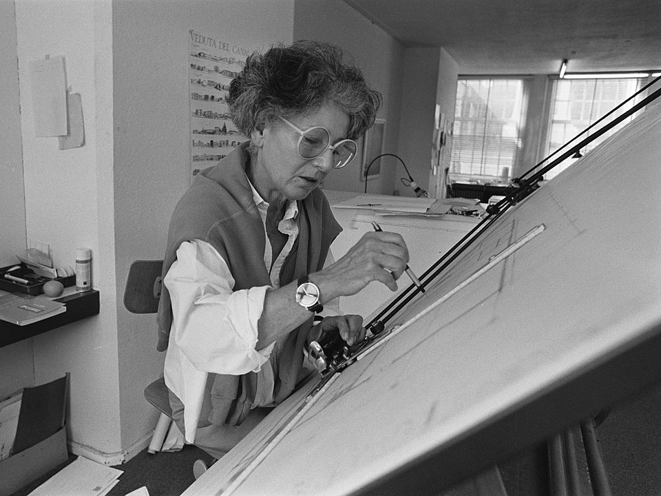 Architecte die met een trekpen aan haar tekentafel werkt